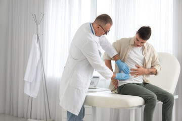 Fototapeta premium Male urologist examining patient on couch in office