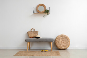 Soft bench with summer accessories near light wall in hall