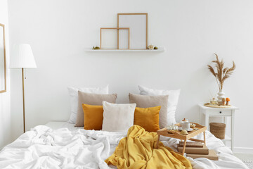 Plaid and tray with tea on bed in cozy bedroom