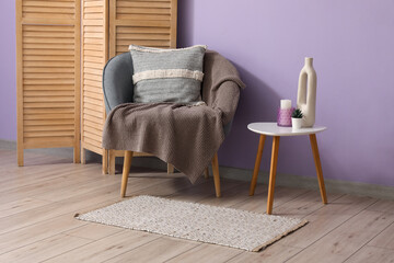 Interior of living room with soft armchair, plaid, coffee table and folding screen