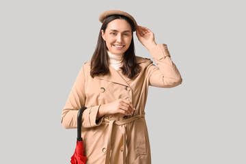 Fototapeta premium Happy young woman with umbrella on grey background