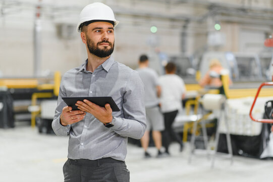 Industrial engineer holding tablet and supervising production line in factory
