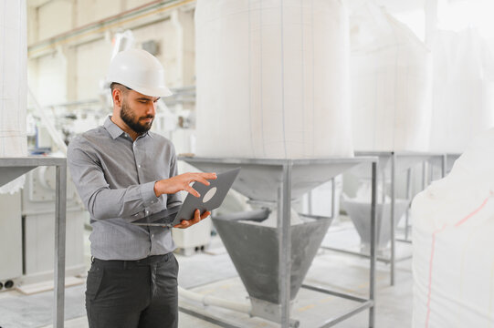 Engineer using laptop, inspecting production in flour mill