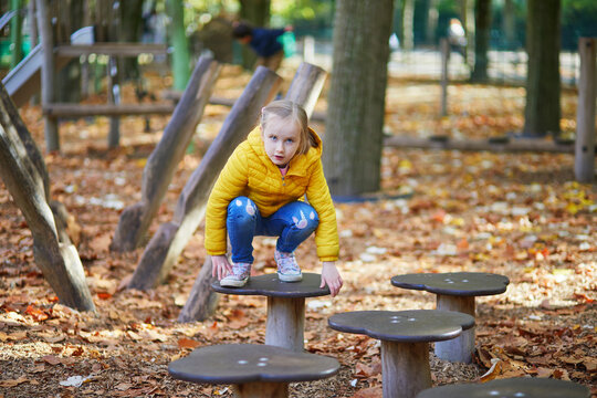 Cheerful little girl having fun on playground in autumn park in Paris, France. - Powered by Adobe