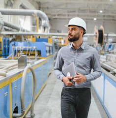 Industrial engineer walking and holding laptop in manufacturing factory