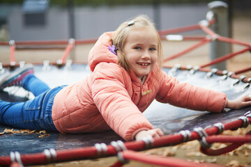 Cheerful little girl having fun on playground in autumn park in Paris, France.