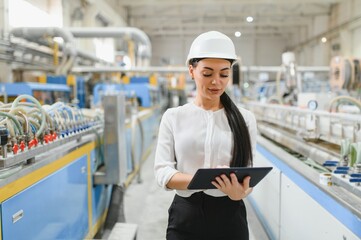 Female engineer using digital tablet, supervising production line in factory
