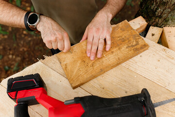 brutal young brunette man, dad with beard is nailing building a tree house to his little son with...