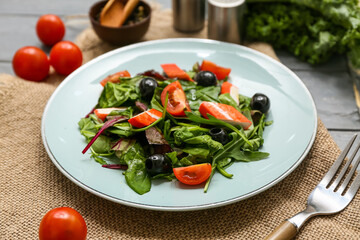 Plate of salad with crab sticks, spinach, black olives and tomatoes on napkin