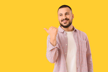 Young man pointing at something on yellow background. Rules concept