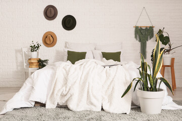 Interior of light bedroom with chair, hats and green plants