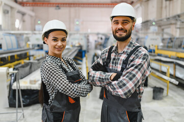 Smiling industrial workers posing with crossed arms in factory