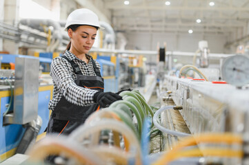 Female factory worker checking green hoses on production line