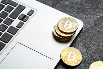 Golden bitcoins with laptop on dark background