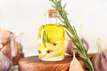 Bottle of fresh garlic oil with rosemary and peppercorns on white background