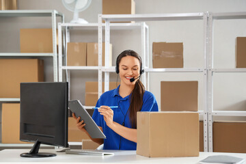 Female worker working with headset at table in warehouse
