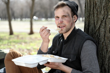 Homeless man eating food in park
