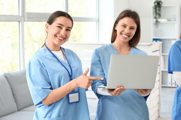 Female medical interns with laptop in clinic