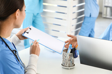 Female medical interns with clipboard at reception in clinic, closeup