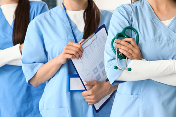 Female medical interns with stethoscope and clipboard in clinic, closeup