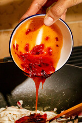 Fiery chili sauce cascades onto sizzling noodles, igniting an umami storm, perfect for Lunar New...
