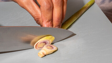 A South Asian woman meticulously slices aromatic lemongrass, evoking Thai culinary celebrations and the vibrant Songkran festival