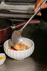 A hand serves steaming shrimp bisque into a fluted porcelain bowl, echoing Lunar New Year...