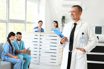 Male doctor with clipboard against medical interns in clinic