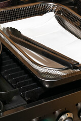Metallic sheen of culinary tongs rest on a paper-lined oven tray, invoking industrial gastronomy...