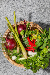 Wicker basket brimming with lemongrass, vibrant chilies, and foraged herbs, capturing harvest...