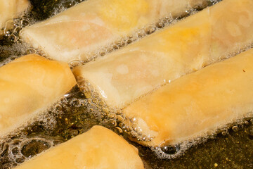 Golden spring rolls sizzling in a bubbling dance, evoking Lunar New Year celebration and crispy...
