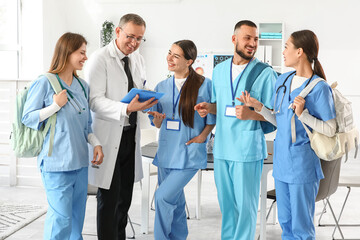 Group of medical interns and doctor with clipboard in clinic
