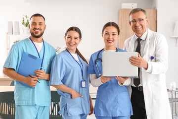 Group of medical interns and doctor with laptop in clinic