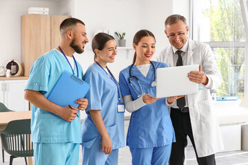 Group of medical interns with doctor using laptop in clinic