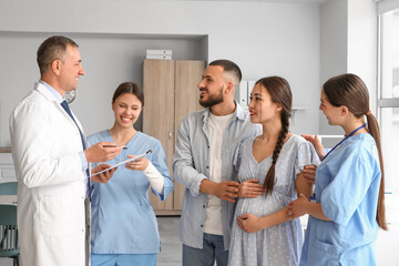 Medical interns and doctor working with pregnant couple in clinic