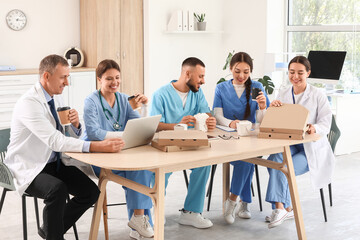 Doctors with medical interns having lunch at table in kitchen