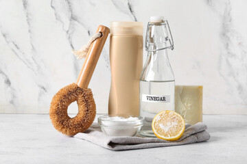 Set of natural cleaning supplies on table near white marble wall