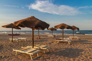 Sun umbrellas and chaise lounges on tropical beach. Concept of rest, relaxation, holidays, resort