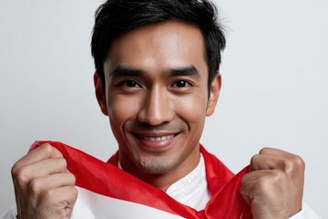 Smiling man holds a red and white flag in front of him with a neutral background