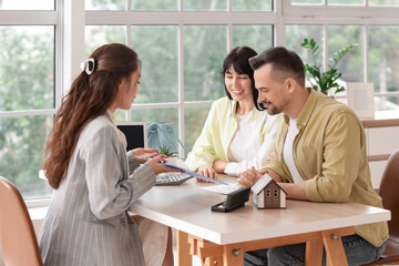 Young couple with real estate agent buying house in office
