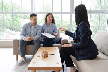Young couple with real estate agent buying house in room