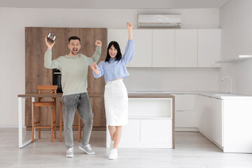 Happy young couple with house model and keys from their new flat in kitchen