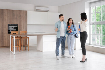 Female real estate agent showing kitchen to couple in new house