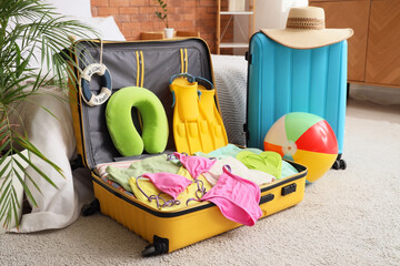 Suitcases with beach accessories in bedroom