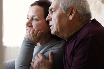 Senior couple using laptop together in the room. Embracing elderly man and woman reading email or online shopping choice. Old man and woman talk at table in home together on internet, social media. 4K