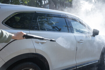washing a dirty car and wheels with water and a pressure washer