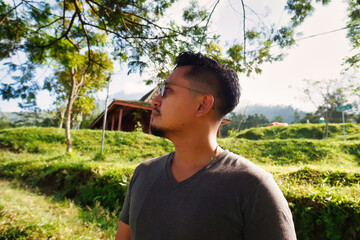 Man Wearing Glasses in a Serene Countryside Landscape with Lush Greenery
