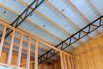 Worker are installing metal framing wooden beams in building under construction