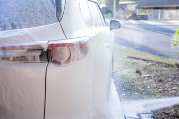washing a dirty car and wheels with water and a pressure washer