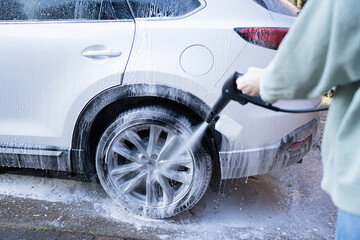 washing a dirty car and wheels with water and a pressure washer